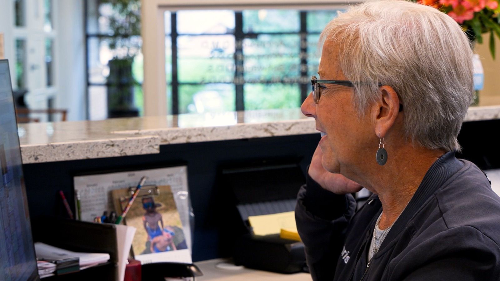 Front desk team member on the phone scheduling a teen patient's appointment in Grand Rapids, MI