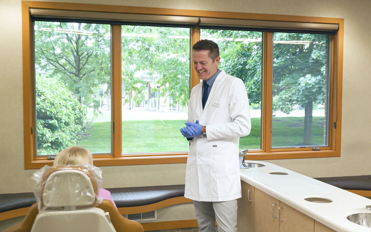 Orthodontist greeting a young child patient for an early checkup in Grandville, MI