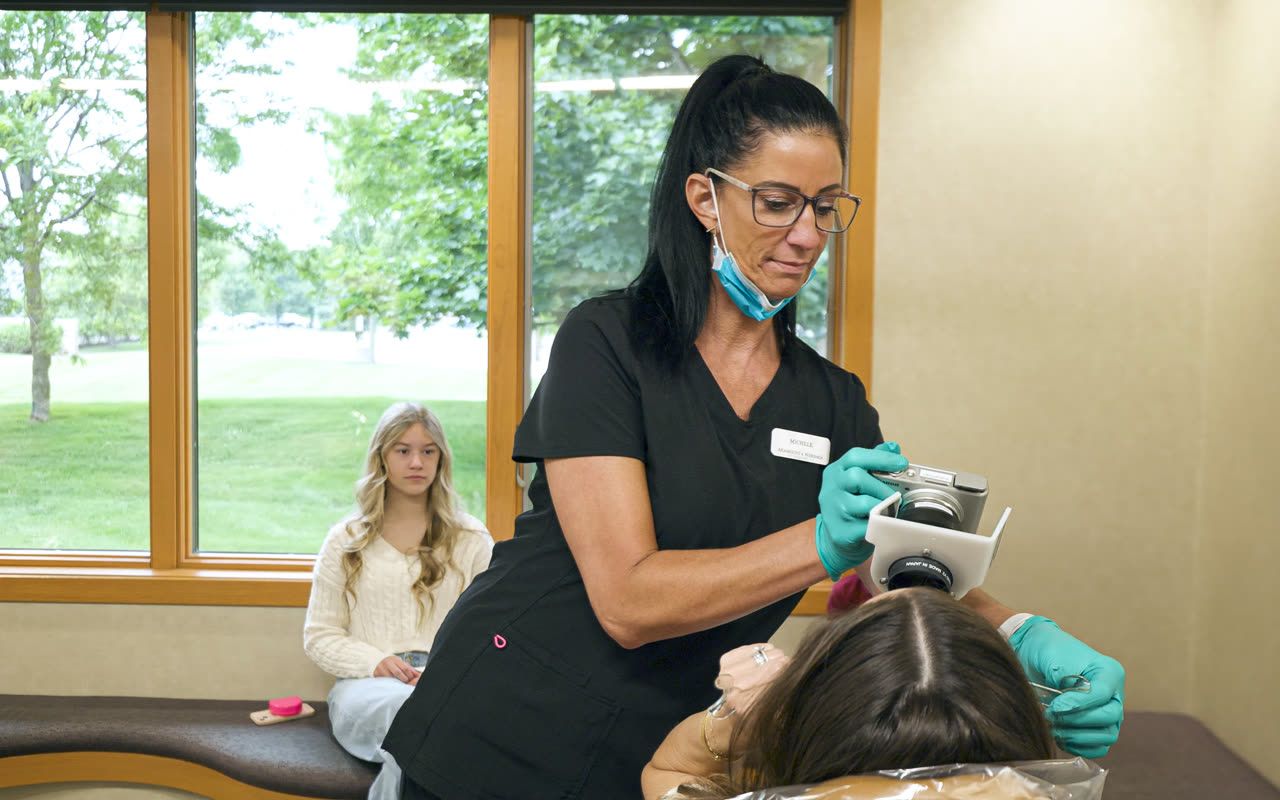 Orthodontic assistant capturing digital photos for a teen patient in Grandville, MI