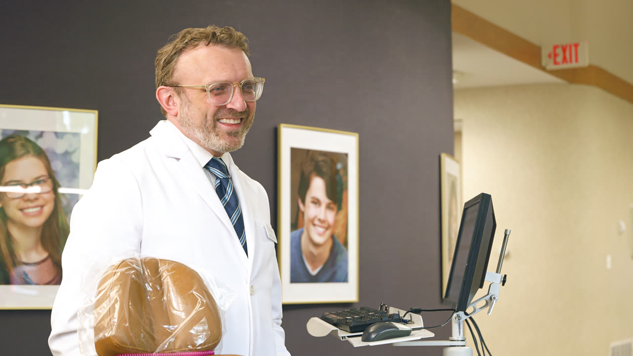 Orthodontist greeting a patient near our patient photo wall at our Grand Rapids, MI office